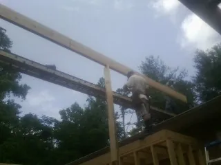 Carpenter setting a ridge beam over a new addition frame — Ice Dam Removal by Roofing Brothers in Midfield