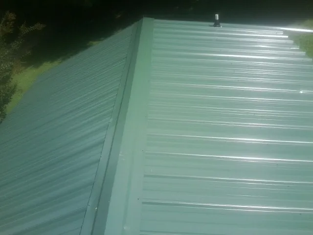 New green metal panels meeting at the ridge of a roof — Flat Roof Repair work by our crew in Midfield