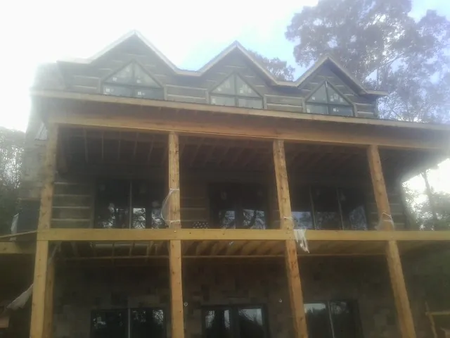 Dormers and porch framing on a large log home under construction — Roof Coating work by our crew in Midfield