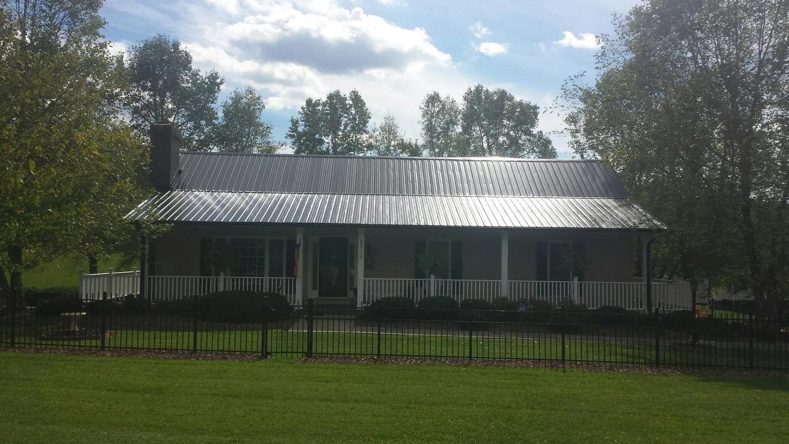 Gray metal roof on a brick ranch with a full width front porch — Gutter Guard Installation work by our crew in Midfield