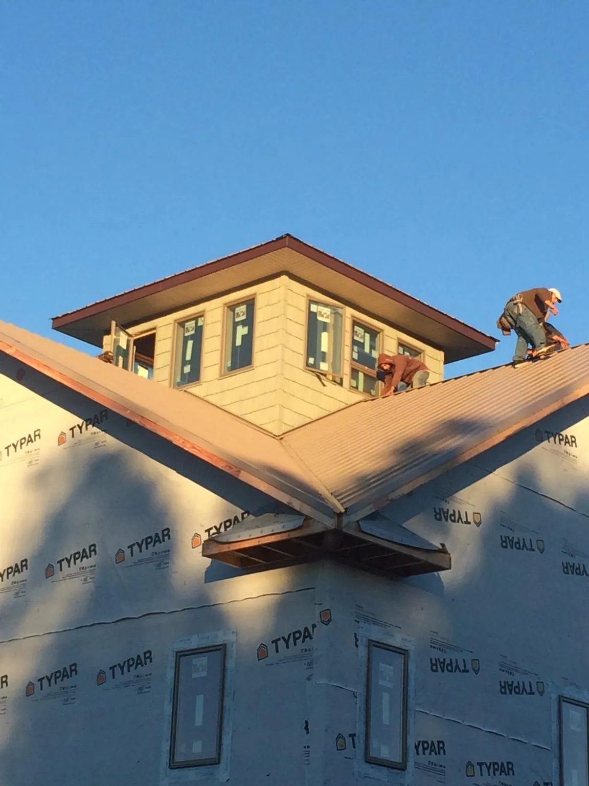 Roofers working around a rooftop cupola on a new metal roof at sunset — Roof Waterproofing in Midfield by Roofing Brothers